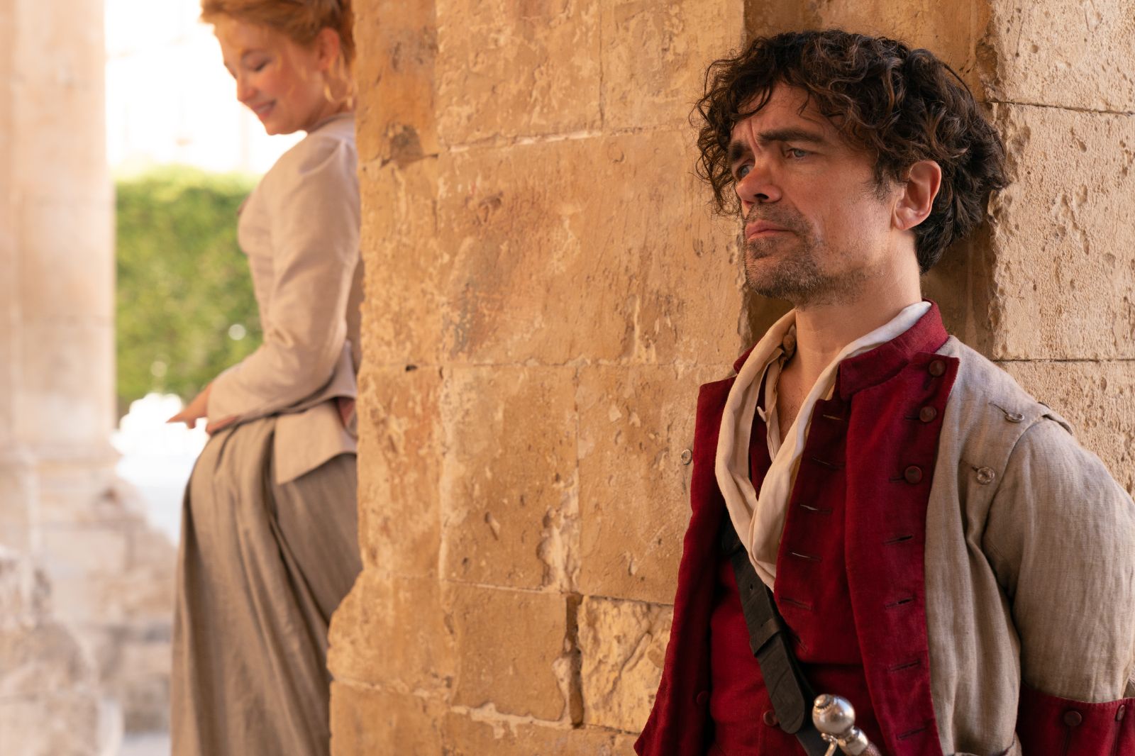 Peter Dinklage As Cyrano in Cyrano de Bergerac Leaning Against A stone pillar of his castle