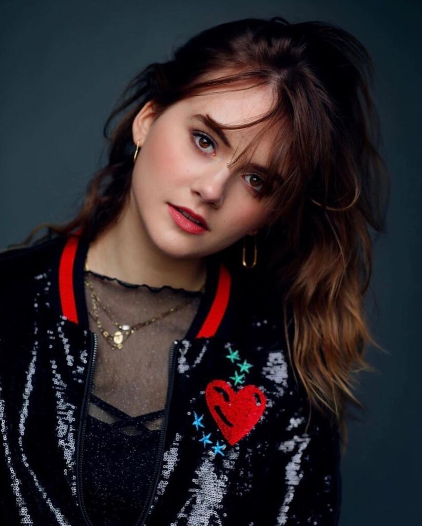 Emilia Jones in a black sequined zip jacket with red heart