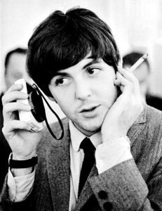 Paul McCartney Listening to a Radio With Cigarette in Hand in the 1960s