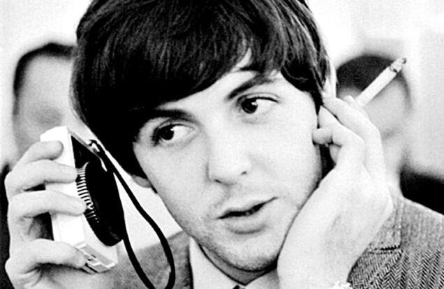 Paul McCartney Listening to a Radio With Cigarette in Hand in the 1960s