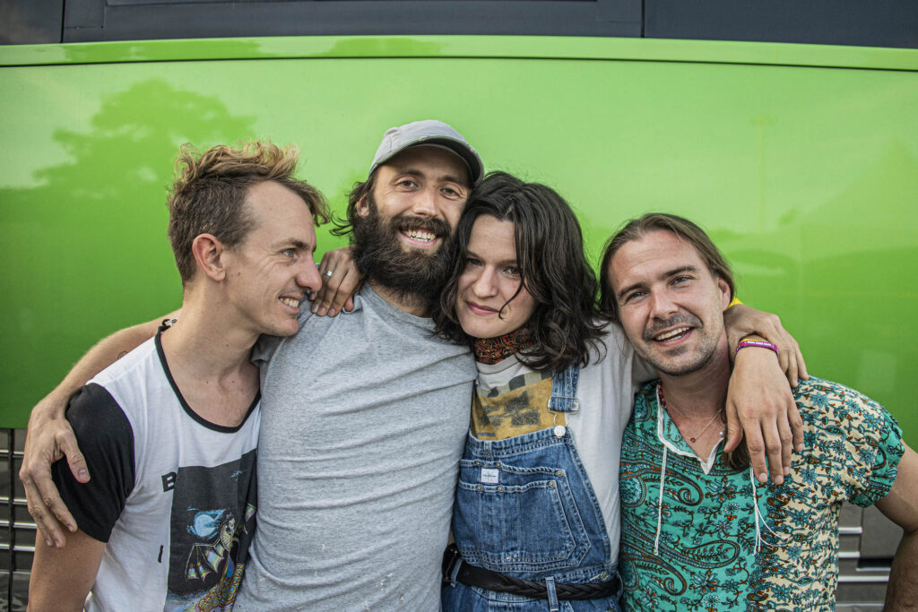 Big Thief Group Hug with Bright Green Wall Behind Them