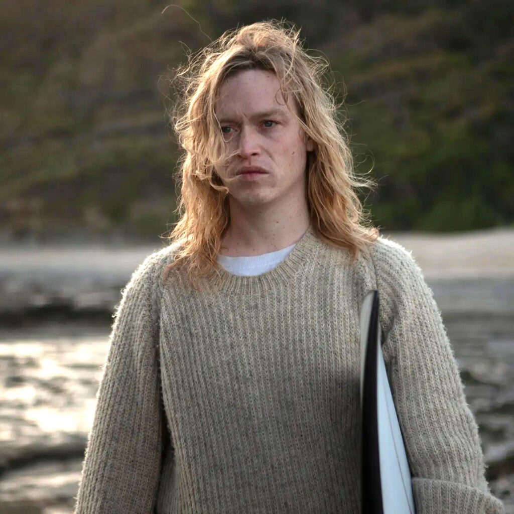 Caleb Landry Jones Starring In Nitram Wearing Beige Sweater Standing on the Beach